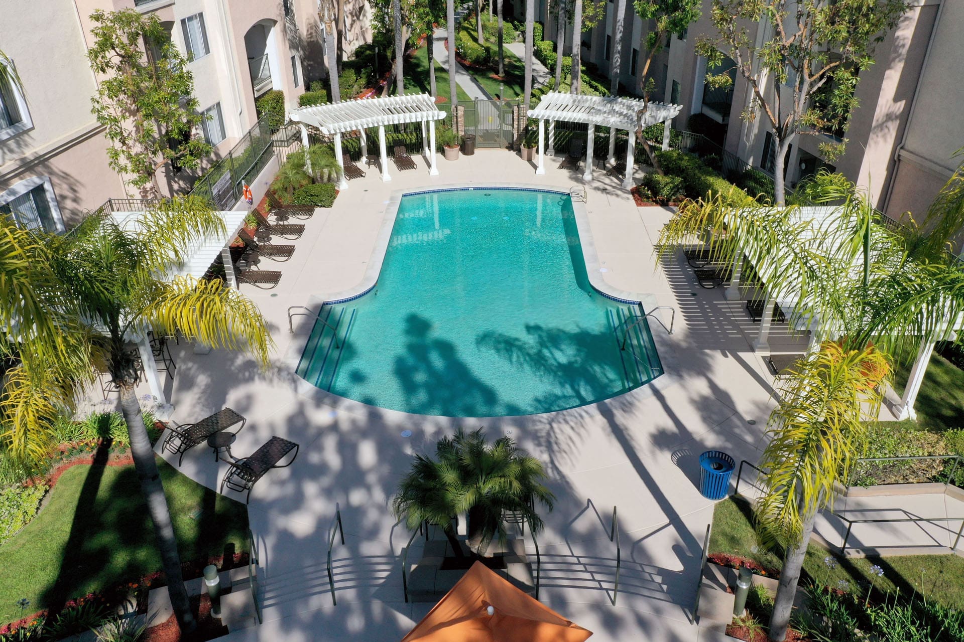 Apartments in Aliso Viejo CA-Aventine Apartments Swimming Pool Surrounded by Palm Trees, Lounge Chairs, and Gazebos